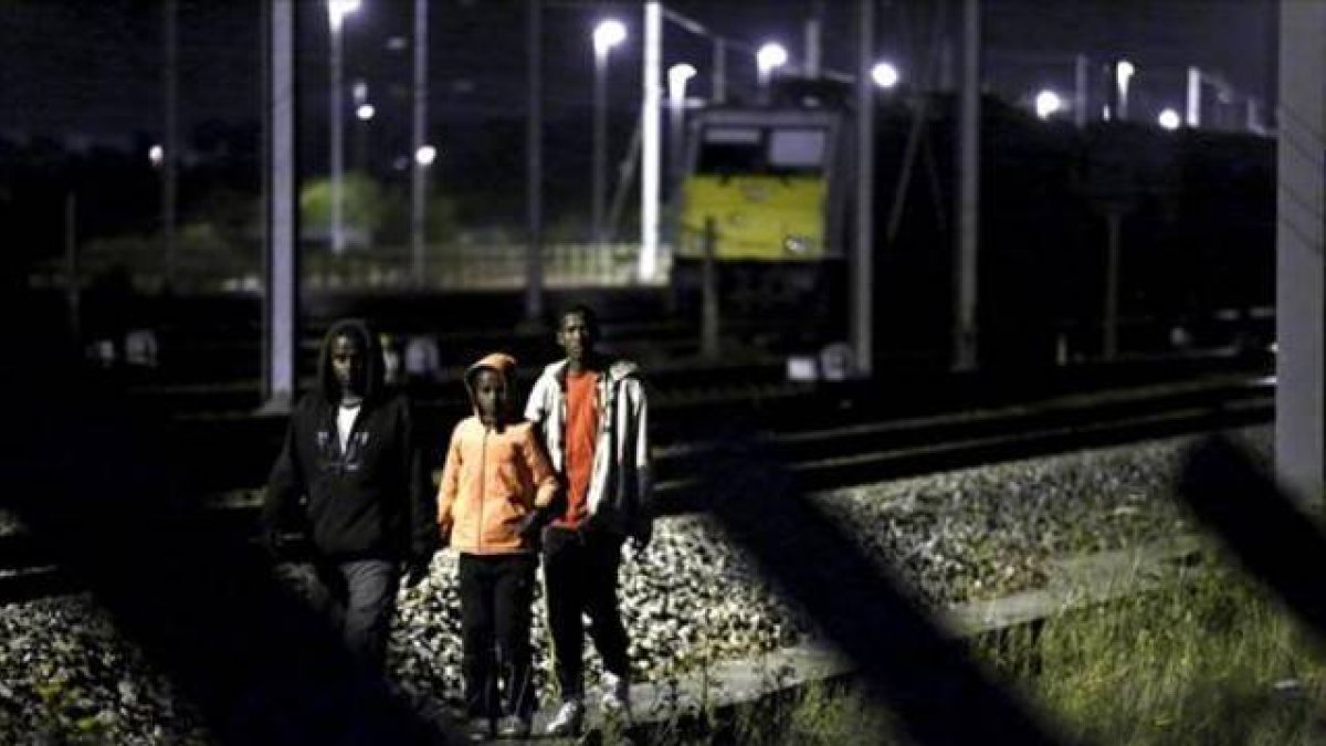 Tres inmigrantes se encaminan por las vías del tren con la intención de acceder al Eurotúnel, cerca de Calais.-REUTERS