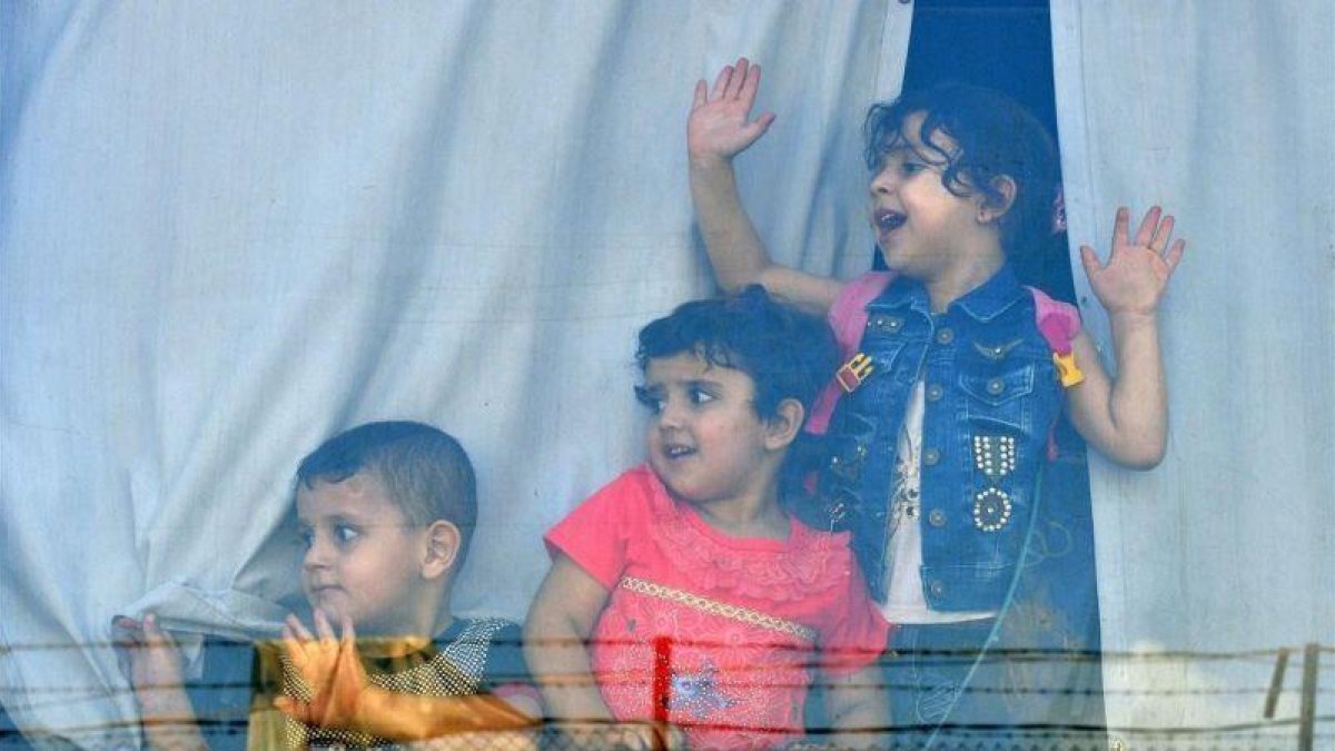 Niños refugiados sirios miran a través de la ventana de un autobús antes de abandonar Beirut este domingo de regreso a sus hogares en Siria.-EFE / WAEL HAMZEH