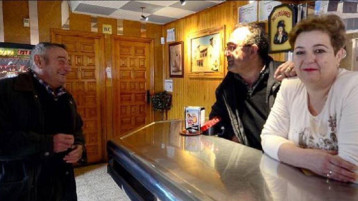 El matrimonio Frías Pérez, tras la barra de su bar a la derecha, reciben la enhorabuena de Juan Gómez, llegado desde Rioseco para darles su felicitación / Á. M.-