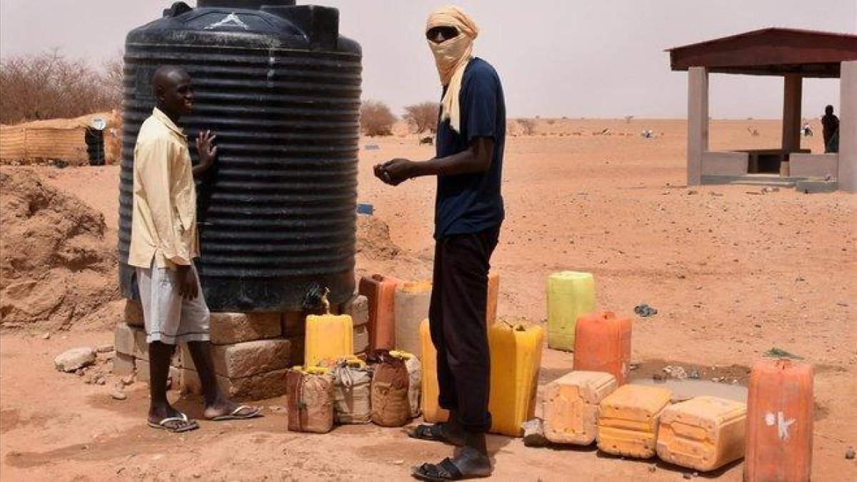 Dos refugiados recogen agua en un tanque en un campo de Níger.-ESMA CAKIR