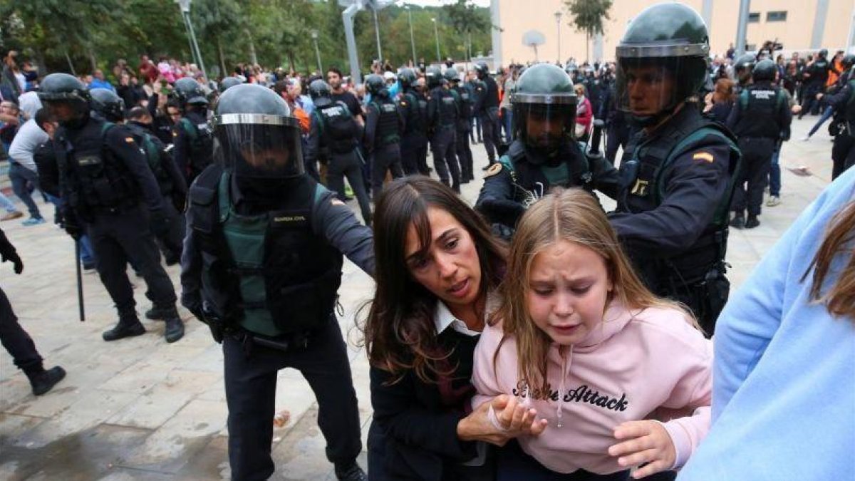 Una madre y su hija huyen tras la carga policial en Sant Julià de Ramis.-ALBERT GEA/REUTERS