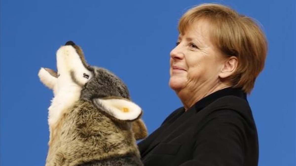 Angela Merkel, con un lobo de peluche con el que ha sido obsequiado en la convención de la CDU en Karlsruhe, este lunes.-AP / MICHAEL PROBST