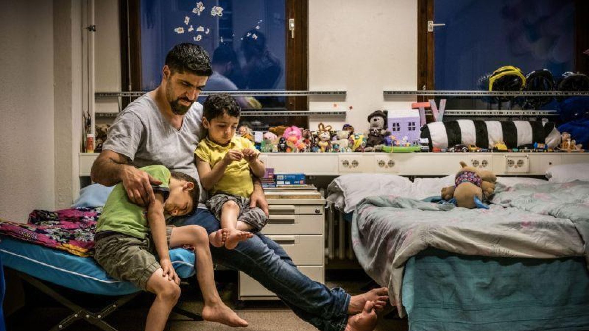 Un refugiado sirio explica cuentos a sus hijos antes de dormir, en un centro de acogida en Prenzlauer Berg (Alemania).-EFE