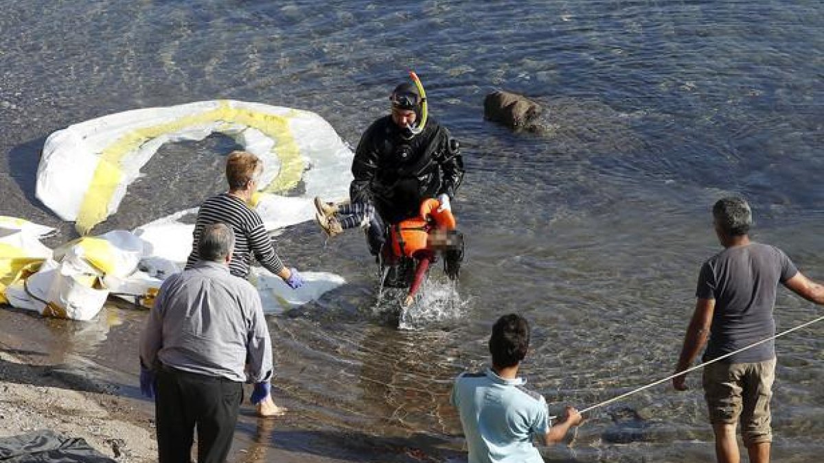 Un guardacostas griego saca del agua el cadáver de un niño refugiado en la costa griega de Lesbos.-REUTERS