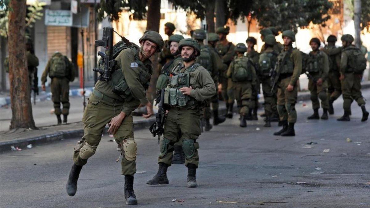 Un soldado israelí lanza un petardo contra un grupo de palestinos en Hebron durante un enfrentamiento, el pasado 13 de octubre.-EFE / ABED AL HASHLAMOUN