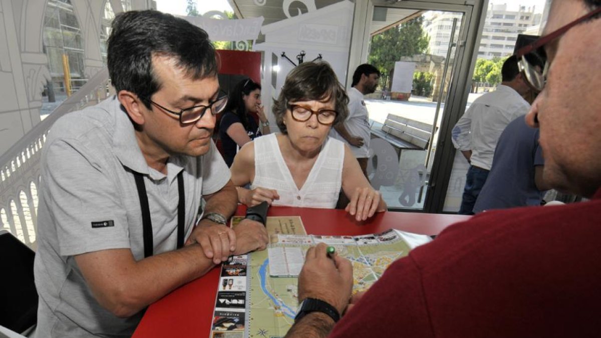 Imagen de un par de turistas echando un vistazo a un mapa en la Oficina de Turismo.-VALENTÍN GUISANDE