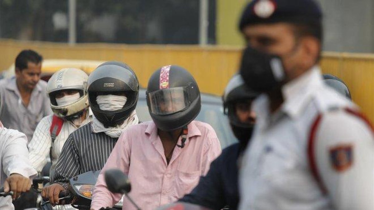 Varios motoristas y un guardia se protegen con mascarillas de la elevada polución, este lunes en Nueva Deli.-MANISH SWARUP (AP)