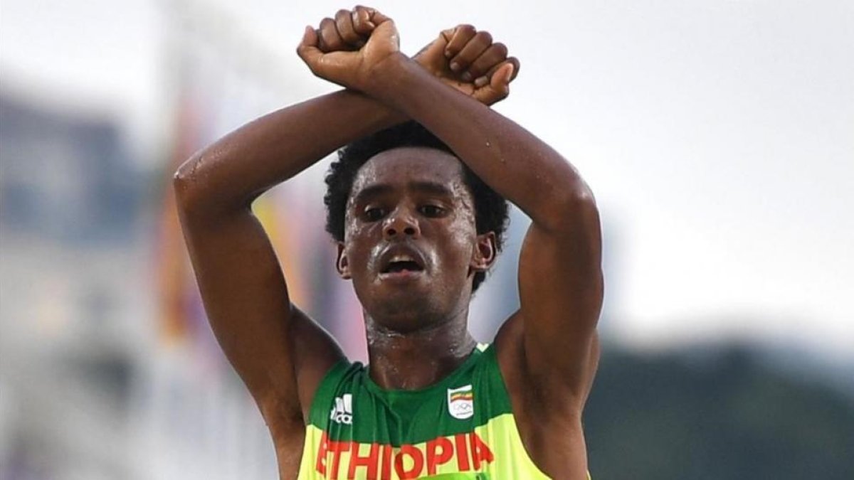 El atleta etíope Feyisa Lilesa cruzando la línea de meta tras acabar segundo en el maratón de Río.-OLIVIER MORÍN / AFP