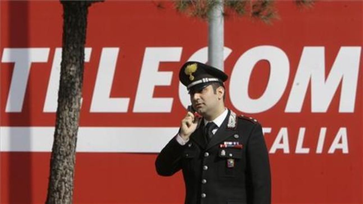 Un policía habla con su móvil frente a la sede de Telecom Italia en Rozzano-AP / LUCA BRUNO