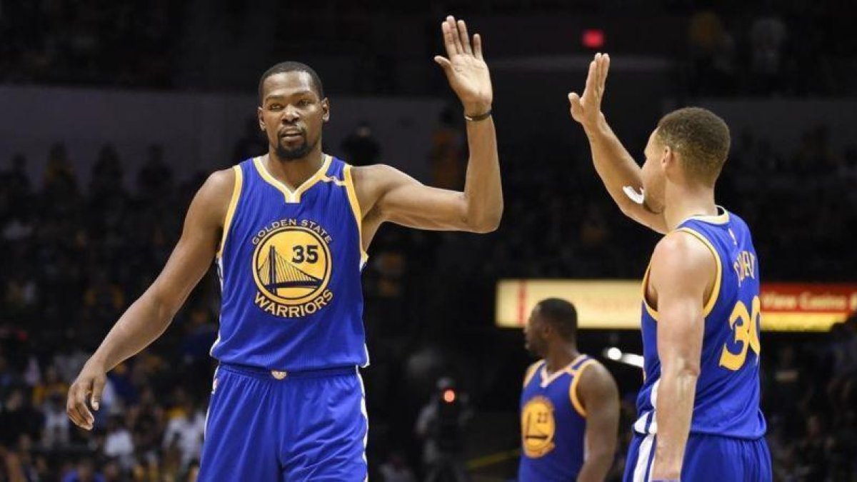 Kevin Durant choca con Stephen Curry durante un partido de pretemporada contra los Lakers.-AP / DENIS POROY