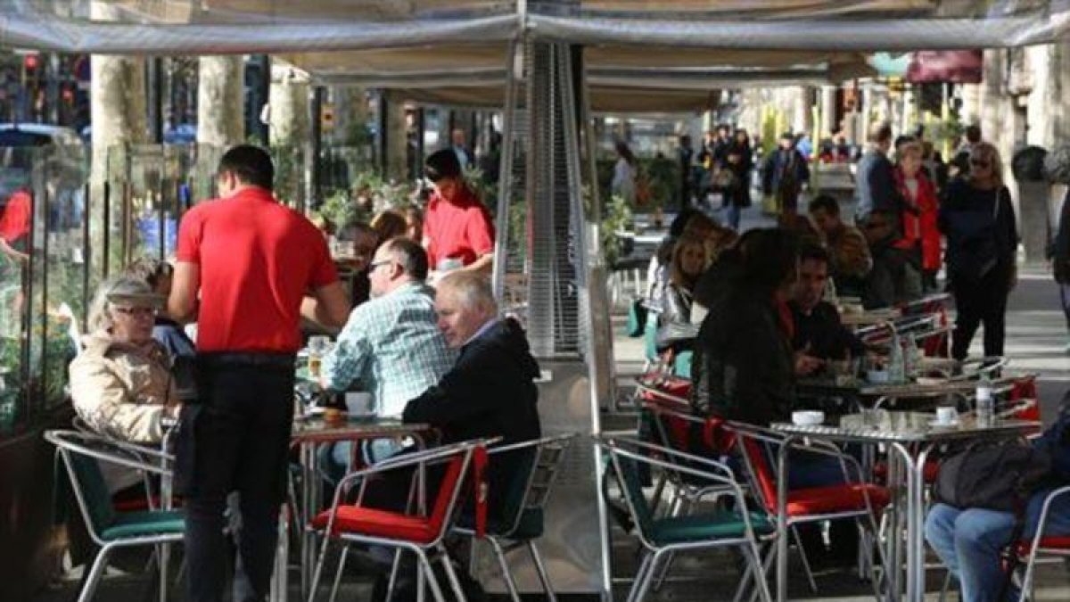 Varios camareros sirven a clientes en terrazas de bares del paseo de Gràcia.-DANNY CAMINAL