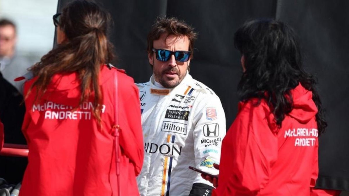 Fernando Alonso conversa con dos componentes del equipo de Mario Andretti, en el test celebrado hoy.-STEVE C MITCHELL