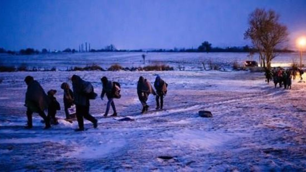 Migrantes y refugiados caminan por un campo cubierto de nieve tras cruzar la frontera de Macedonia con Serbia, cerca de la población de Miratovac, este domingo.-AFP / DIMITAR DILKOFF