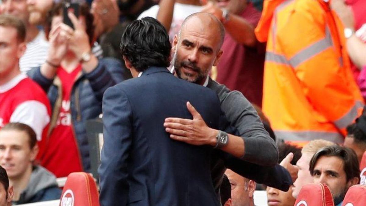 Pep Guardiola y Unai Emery (de espaldas) se saludan antes del Arsenal-Manchester City.-REUTERS / JOHN SIBLEY