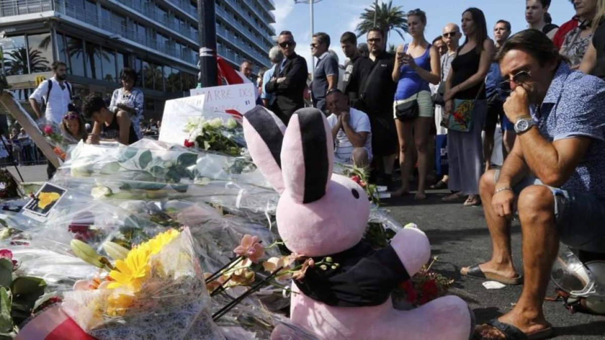 Varias personas colocan flores, velas y un peluche en tributo a las víctimas del atentado en Niza, este viernes.-REUTERS / PASCAL ROSSIGNOL