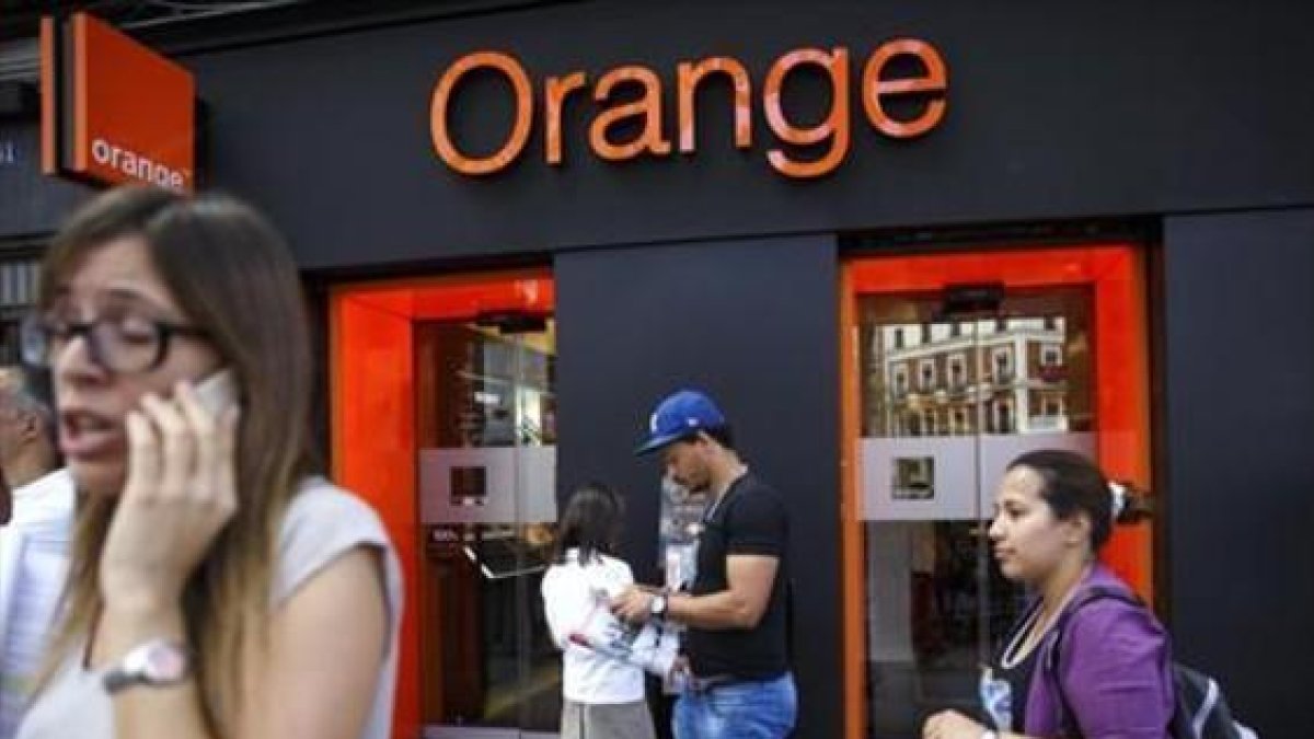 Personas pasan por delante de una tienda de Orange en Madrid.-REUTERS / ANDREA COMAS