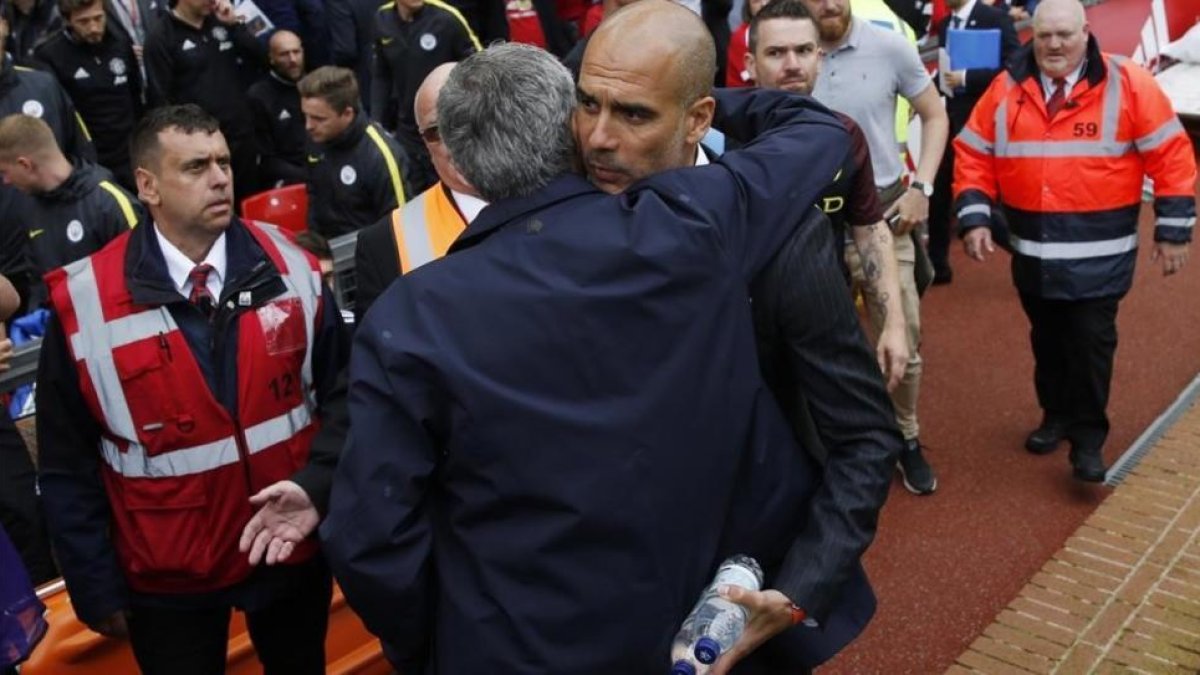 Mourinho y Guardiola se abrazan antes de empezar el derbi de Manchester.-REUTERS / CARL RECINE
