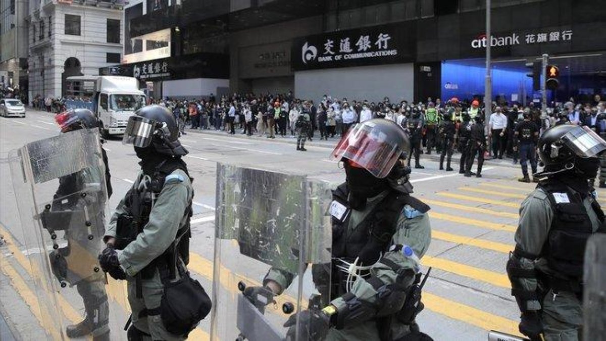 Policía antidisturbios vigila a manifestantes en el distrito financiero de Hong Kong.-KIN CHEUNG (AP)