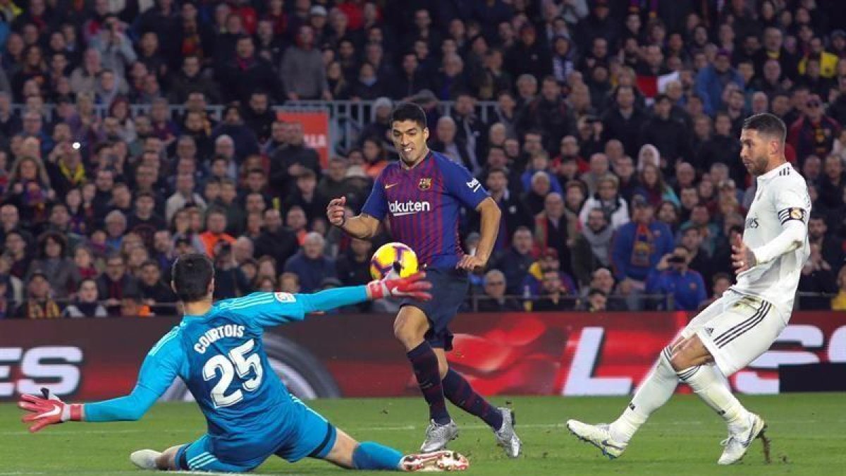 Suárez pica el balón ante Courtois en una imagen de archivo.-ENRIC FONTCUBERTA (EFE)