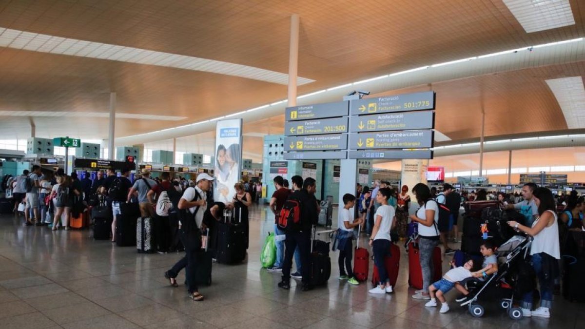 Colas de pasajeros esperando para facturar en los mostradores de Vueling en la T-1 del aeropuerto de El Prat.-JOSEP GARCIA