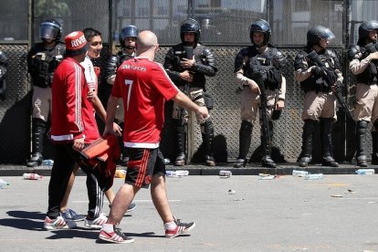 Aficionados del River pasan por delante de las fuerzas policiales tras la suspensión del partido el pasado sábado.-AGUSTÍN MACARIAN