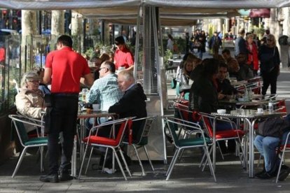 Un camarero atiende a clientes en una terraza. Es el colectivo con más contratos temporales.-DANNY CAMINAL