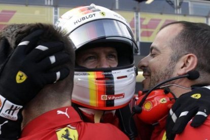 Sebastian Vettel es felicitado por dos de sus mecánicos tras lograr su tercera pole consecutiva de la temporada.-AP / LUCA BRUNO