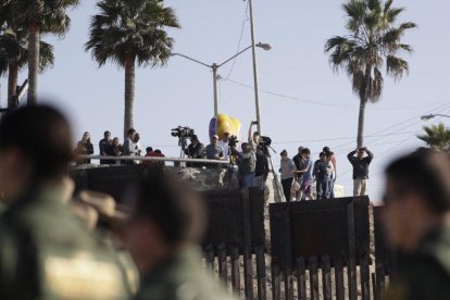 Migrantes en Tijuana, México, miran desde el otro lado del muro durante una visita de la Secretaria de Seguridad, Kirjsten Nielsen.-GREGORY BULL (AP)