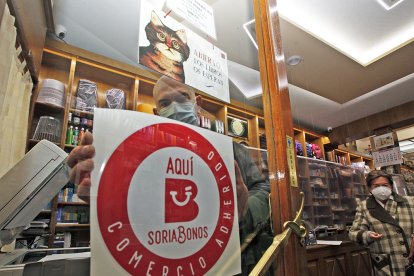 César Millán, de la librería Las Heras, coloca el distintivo de Soria Bonos. MARIO TEJEDOR