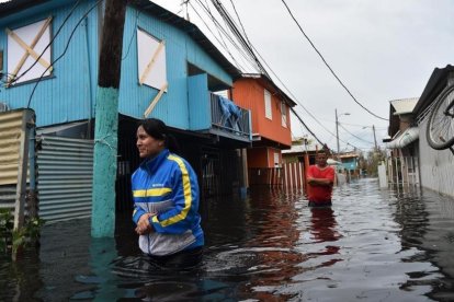 Dos personas caminan por una calle inundada en Juana Matos (Puerto Rico), el 21 de septiembre.-AFP / HECTOR RETAMAL