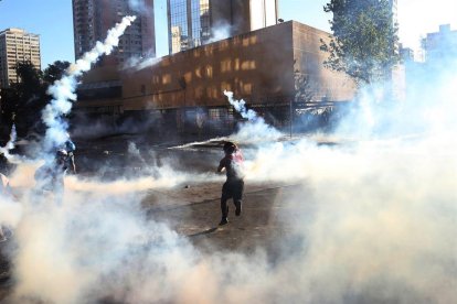 Un grupo de personas se enfrenta a la policía antidisturbios, este viernes, en la Plaza Italia en Santiago de Chile durante una nueva jornada de protestas en contra del gobierno del presidente Sebastián Piñera.-EFE / ELVIS GONZÁLEZ