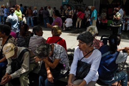 Un grupo de venezolanos hacen cola frente a un banco de Caracas para cobrar sus pensiones.-FEDERICO PARRA