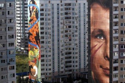 En primer plano, el retrato del cosmonauta Yuri Gagarin obra del italiano Jorit Agoch, en Odintsovo.-EFE / MAXIM SHIPENKOV