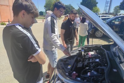 Alumnos participantes en la jornada mirando el motor del coche.-HDS