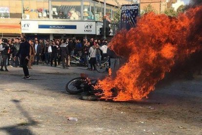 Manifestantes iranís junto a una motocicleta quemada en Isfahan (Irán).-AFP