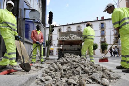 En la imagen algunos trabajadores extranjeros realizando actuaciones en el firme de una de las calles del centro de la capital. / VALENTÍN GUISANDE-