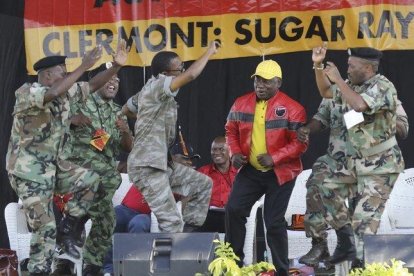 El presidente sudafricano y líder del Congreso Nacional Africano, Cyril Ramaphosa (con chaqueta roja) baila con unos militares durante un mitin de su partido en la ciudad de Durban.-ANTOINE CHAUVEL (AP)