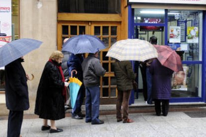 Aprovechando las últimas compras navideñas y a pesar de la lluvia muchos sorianos hicieron colas en las administraciones más céntricas de la capital para adquirir sus décimos. / ÚRSULA SIERRA-