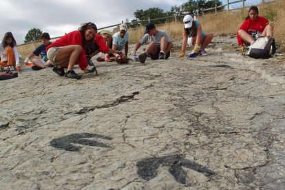 Jóvenes limpiando las huellas de un dinosaurio-HDS
