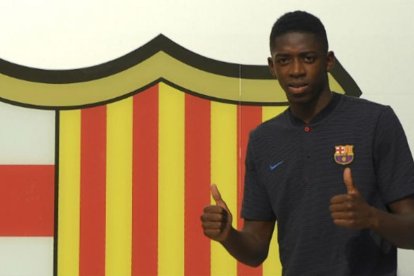 Dembelé posa ante el escudo del Barça en las oficinas del Camp Nou.-AFP / LLUÍS GENÉ