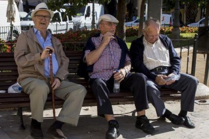 Tres jubilados descansan en un banco de un parque en Valencia.-MIGUEL LORENZO