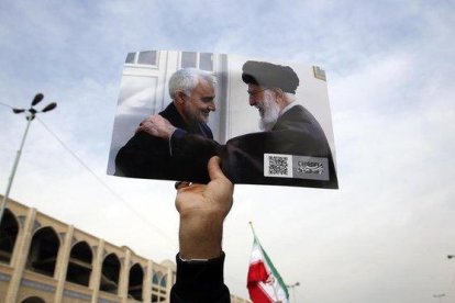 Un manifestante muestra la foto del guía supremo, Alí Jamenei, junto al general Qasim Soleimani.-EFE / ABEDIN THAERKENAREH