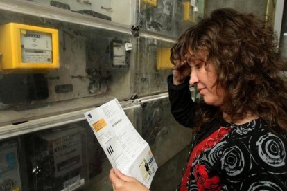 Una mujer comprueba la lectura del contador de electricidad.-ÁLVARO MONGE