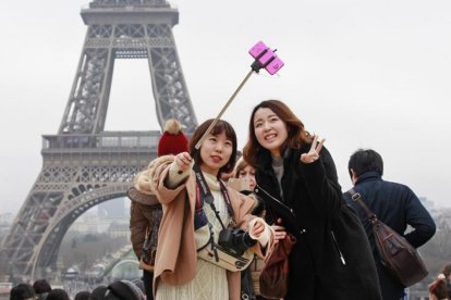 Un grupo de turistas orientales ante la Torre Eiffel.-