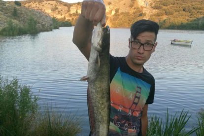 Un aficionados con un siluro capturado en el embalse de Los Rábanos.-CEDIDA