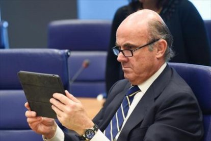 Luis de Guindos mira su tableta durante una reunión del Eurogrupo celebrada en Luxemburgo.-AFP