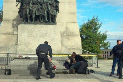 Unos soldados atienden a un compañero herido, ante el monumento de los veteranos de guerra en Ottawa.-Foto: EL PERIÓDICO