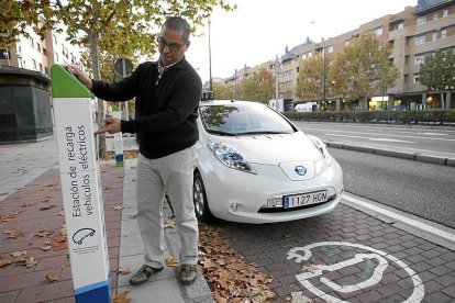 Un hombre utiliza un puesto de recarga de coche eléctrico.-ICAL