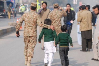 Un soldado paquistaní escolta a dos niños rescatados de la escuela que ha sufrido el ataque en Peshawar.-Foto: REUTERS / KHURAM PARVEZ