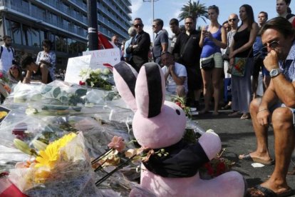 Varias personas colocan flores, velas y un peluche en tributo a las víctimas del atentado en Niza, este viernes.-REUTERS / PASCAL ROSSIGNOL